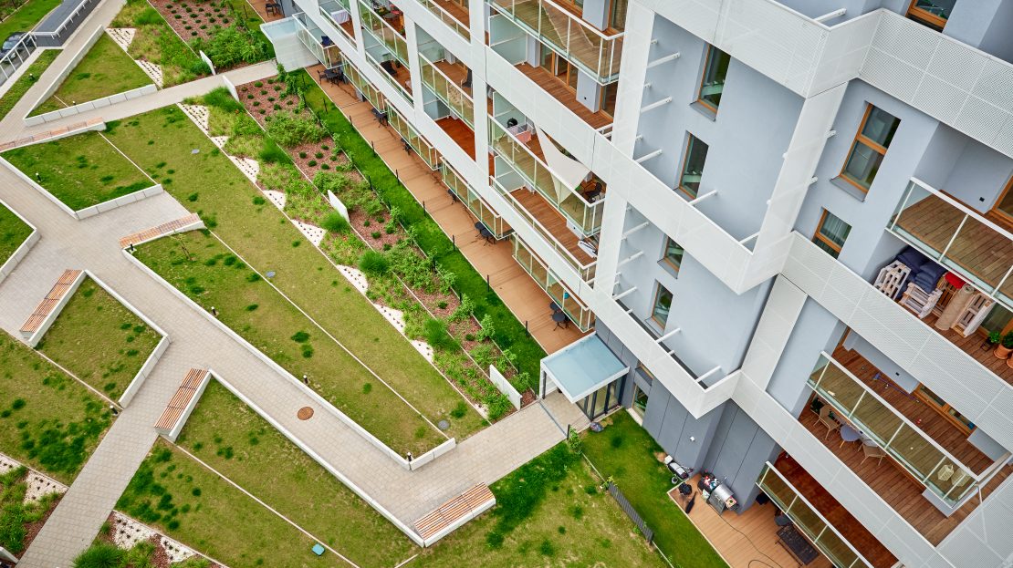 Vue en plongée sur une résidence moderne avec balcons en bois et jardin paysager géométrique.