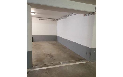 Place de parking intérieure dans un garage sécurisé avec sol béton.
