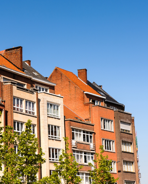 Façades de résidences urbaines en briques rouges sous un ciel bleu, typiques de l’architecture résidentielle au Luxembourg.