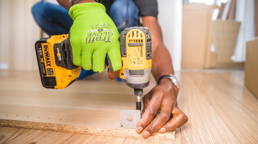 un homme qui fait du bricolage avec une perceuse et des gants