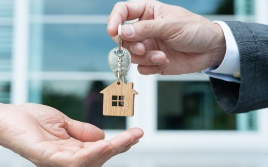 personne qui donne à une autre un porte clé avec une maison miniature