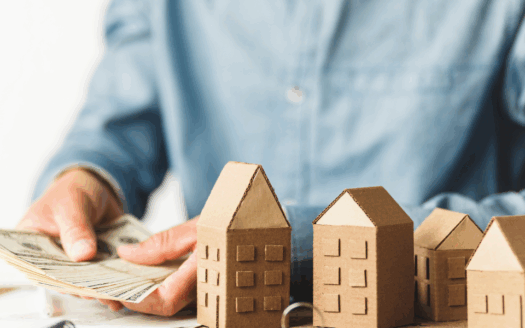 maquettes maison en bois sur une table pendant qu'un homme compte ses billets