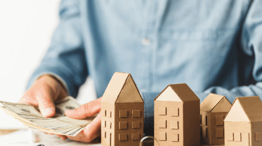 maquettes maison en bois sur une table pendant qu'un homme compte ses billets